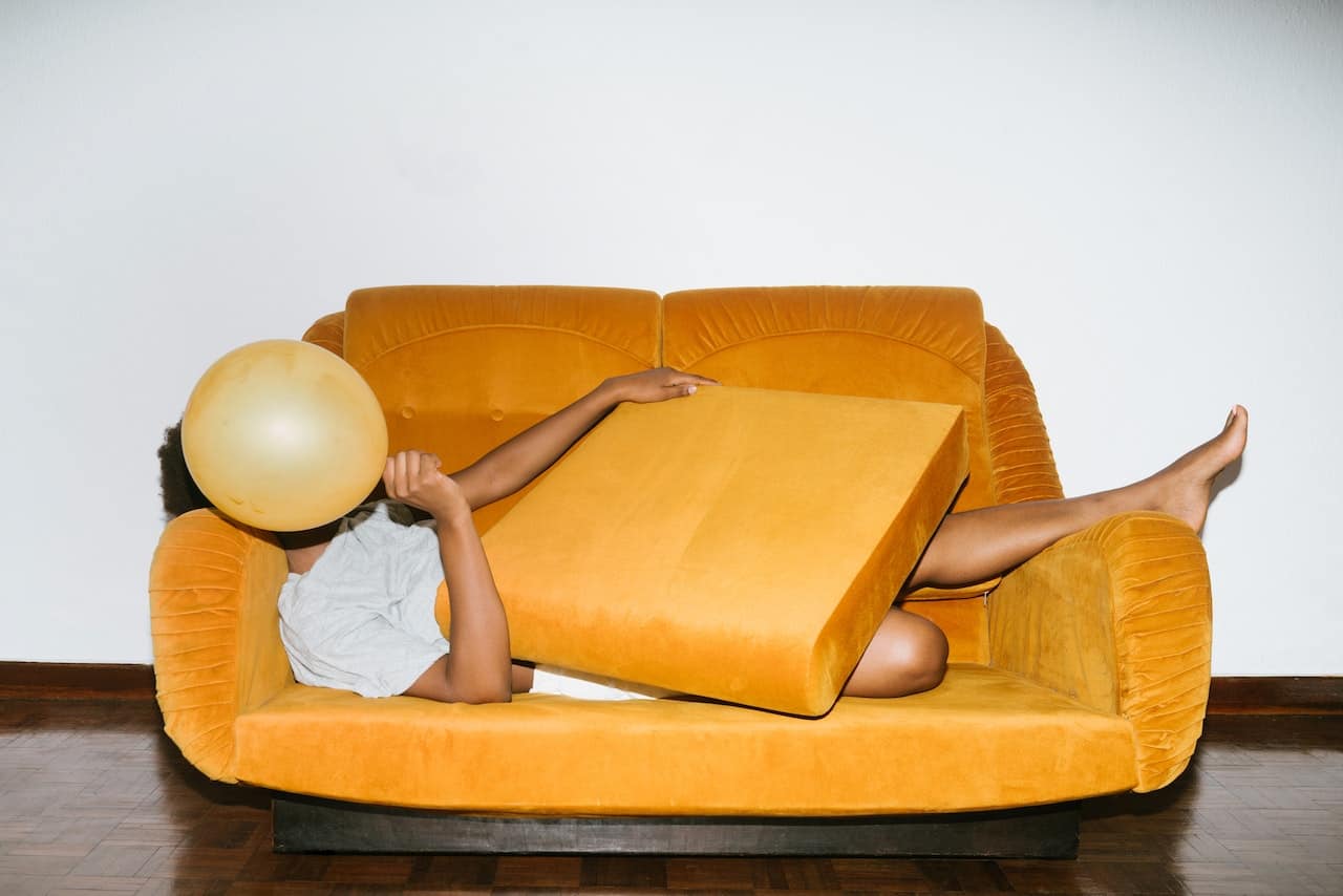 una mujer intentando esconderse bajo un sofa