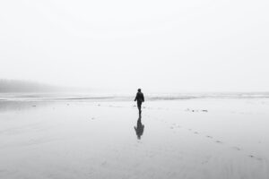 persona lejana en una playa en blanco y negro